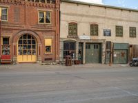 a red fire hydrant sitting in front of an old store window and building next to an open air field