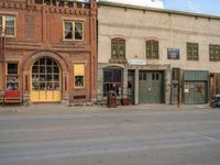 a red fire hydrant sitting in front of an old store window and building next to an open air field