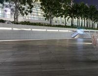 a building sits in front of several trees and lights are on and around it, along with multiple water fountains