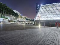 a modern building in the city at night with its lit up lights on and walkway