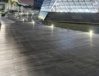 a modern building in the city at night with its lit up lights on and walkway