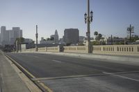 an empty highway with power lines leading to city buildings in the back ground and road tracks