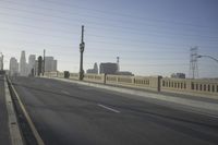 an empty highway with power lines leading to city buildings in the back ground and road tracks