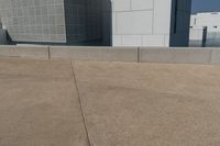two skate boards are parked on a concrete area with the side of a building in the background