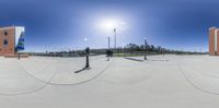 three people skateboarding in a skate park with a sky background and light poles and buildings