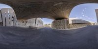 a skateboarder jumps off the side of a ramp in a skate park below a bridge