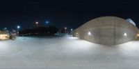 a skate board park with concrete and lights at night as a blurry image shows