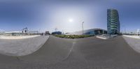 a fish eye shot of a skate park and a high rise building at an angle