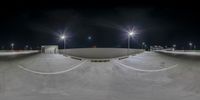 a skate park at night with lights on and empty ramps on either side of it