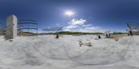 a skate park that is full of people in the sand with their boards on it