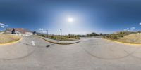 a skateboarder skating on the sidewalk of a skate park near some buildings and a blue sky