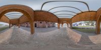 a circular view of a skate park with arches and brick pillars, on an overcast day