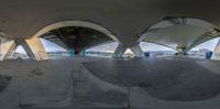 a person skateboarding at an empty skate park with ramps and arches in the foreground