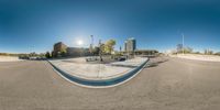 a 360 - view photograph of a skate park and ramp with ramps and buildings in the background