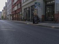 a person riding a skateboard down the middle of a street with buildings on both sides of it