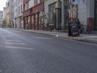 a person riding a skateboard down the middle of a street with buildings on both sides of it