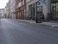 a person riding a skateboard down the middle of a street with buildings on both sides of it