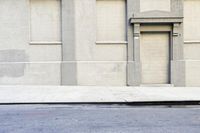 a man on a skateboard in front of an apartment building, with a sidewalk and street lights
