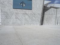 a man riding his skate board in front of a concrete building on the road with graffiti on the walls