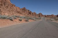 a man riding his skateboard down the middle of a narrow desert road in the mountains