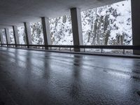 a person riding a skate board on top of a frozen street beneath a bridge over a snowy mountain