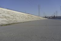 a skateboard on the ground in front of an overpassed dam near a bridge