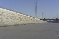 a skateboard on the ground in front of an overpassed dam near a bridge