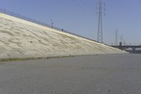 a skateboard on the ground in front of an overpassed dam near a bridge