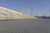 a skateboard on the ground in front of an overpassed dam near a bridge