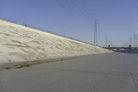 a skateboard on the ground in front of an overpassed dam near a bridge