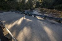 a skateboard sits on top of a railing over a river near a sidewalk and a walkway