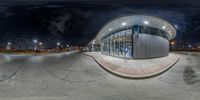 a skateboard park with a building at night in the background and a dark sky