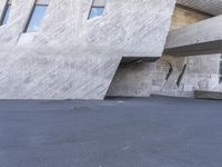 a skate board parked in front of a big concrete building's face with white walls