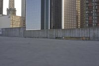 a skateboard is parked on the concrete in front of some tall buildings and some skyscrapers