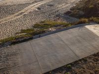 skateboard ramp on the beach surrounded by sand and trees near a body of water