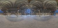 a skateboard ramp that is covered with glass panels and concrete flooring with chandelier, and two circular mirrors