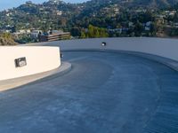 a skate board ramp sits on the side of a roof over a city and mountain