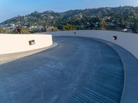 a skate board ramp sits on the side of a roof over a city and mountain