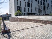 a person riding a skate board with a building in the background on a brick walkway