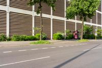 a person on a skateboard rides along an empty street with several trees and buildings