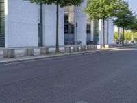 a person riding a skate board near the side of a road in front of an office building