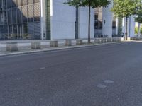 a person riding a skate board near the side of a road in front of an office building