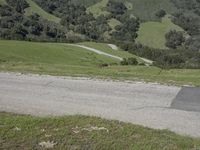 a person riding a skateboard on the road in the mountains between the green hills