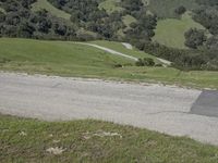 a person riding a skateboard on the road in the mountains between the green hills