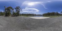 a skateboard is sitting in the middle of a gravel trail, with a sky background