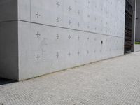 an individual doing a skateboard trick while other person looks on from the sidewalk in front of them
