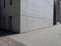 an individual doing a skateboard trick while other person looks on from the sidewalk in front of them
