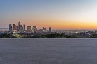 a skateboarder is riding on the asphalt near city skylines in background at sunset