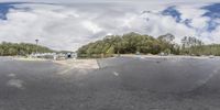 a skateboarder doing tricks at a parking lot near trees with boats in background