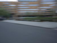 a blurry photo of a man skateboarding on a city street with buildings in the background